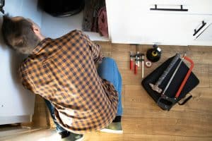 Plumber repairs plumbing pipes in kitchen sink. Removing blockage clog in drain pipe. Replacement of